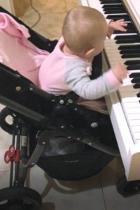 Mariah at 7 months. Using the safety of the pram when reaching the keys.